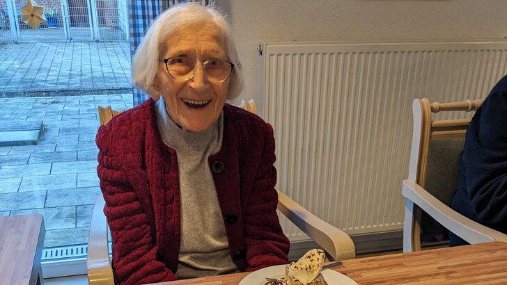 Seniorin am geschmückten Kaffeetisch